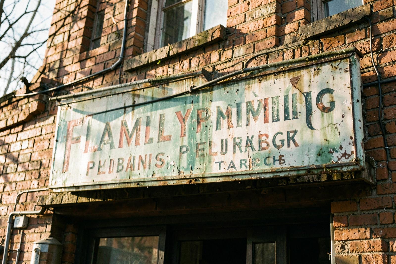 Faded painted sign on a family plumbing shop that has hung on the same brick building for thirty years
